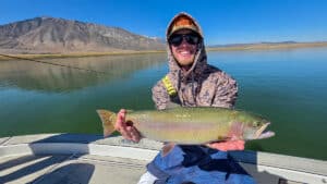 A fly fisherman holding a large cuthhroat trout in a boat on Crowley Lake near Mammoth Lakes, CA