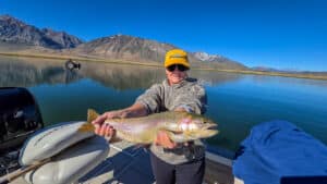 A fly fisherman holding a large cuthhroat trout in a boat on Crowley Lake near Mammoth Lakes, CA