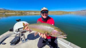 A fly fisherman holding a large cuthhroat trout in a boat on Crowley Lake near Mammoth Lakes, CA