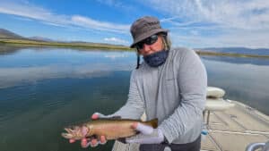 A fly fisherman holding a large cuthhroat trout in a boat on Crowley Lake near Mammoth Lakes, CA