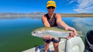A fly fisherman holding a large rainbow trout in a boat on Crowley Lake near Mammoth Lakes, CA