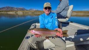 A fly fisherman holding a large cuthhroat trout in a boat on Crowley Lake near Mammoth Lakes, CA