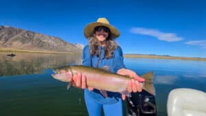 A fly fisherman holding a large cuthhroat trout in a boat on Crowley Lake near Mammoth Lakes, CA