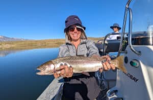 A fly fisherman holding a large cuthhroat trout in a boat on Crowley Lake near Mammoth Lakes, CA