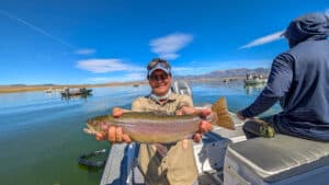 A fly fisherman holding a large cuthhroat trout in a boat on Crowley Lake near Mammoth Lakes, CA