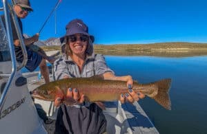 A fly fisherman holding a large cuthhroat trout in a boat on Crowley Lake near Mammoth Lakes, CA