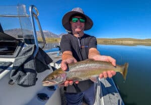A fly fisherman holding a large cuthhroat trout in a boat on Crowley Lake near Mammoth Lakes, CA
